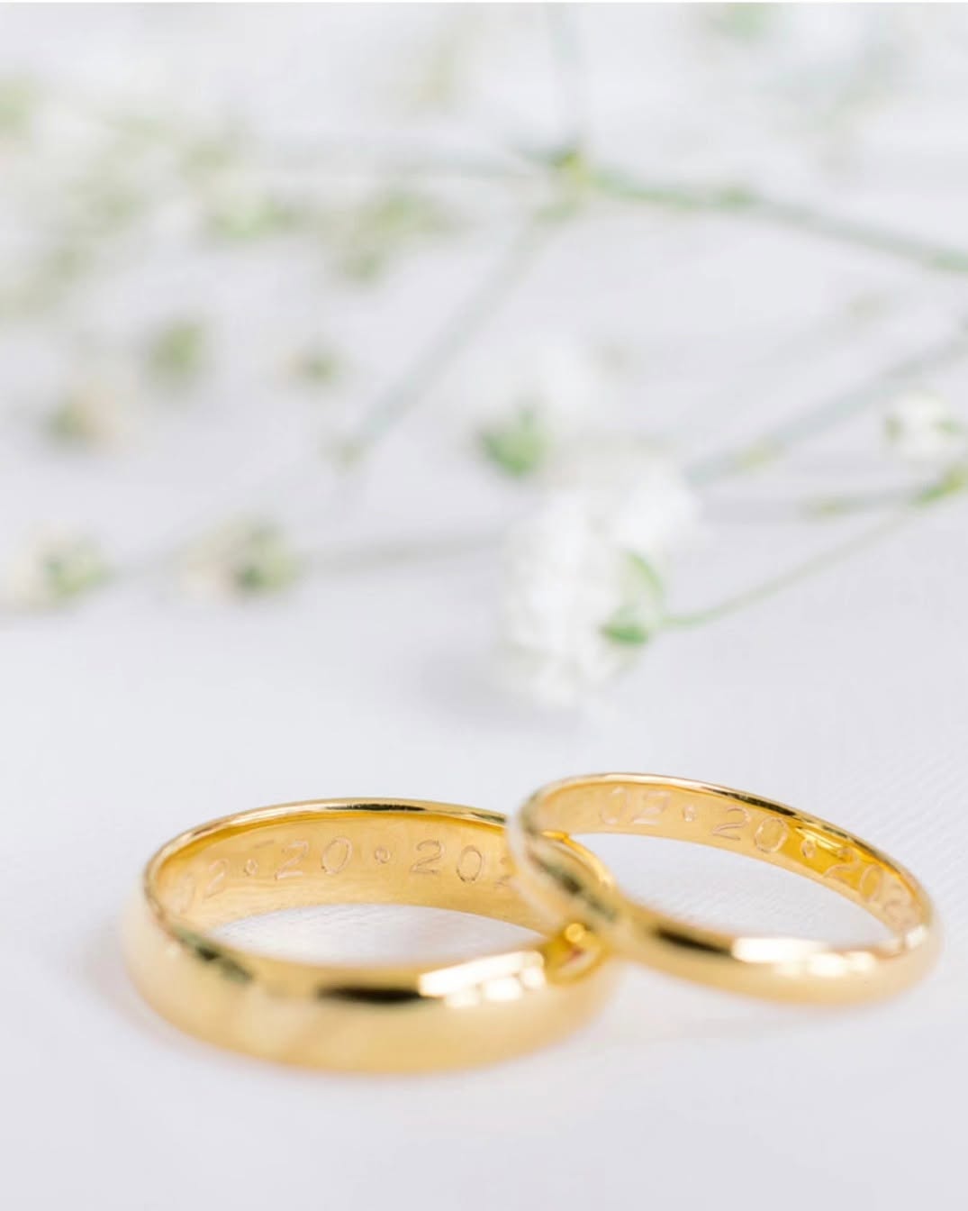 Gold wedding bands beside baby's breath